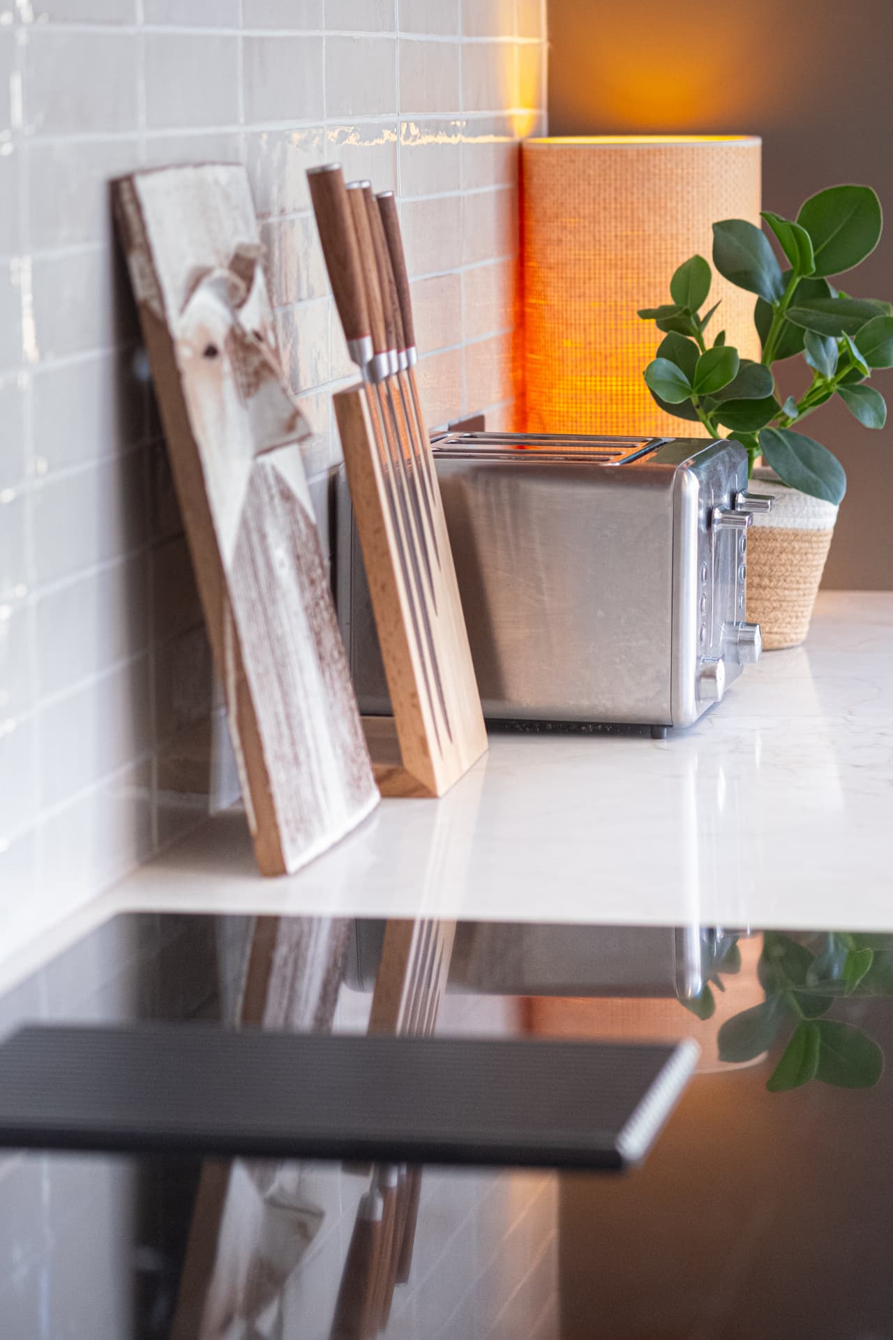 Marble worktop detail with chopping board, knife block and toaster in a light tiled kitchen
